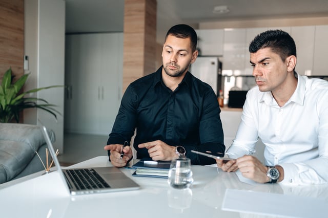 Two employees finding solution to problem on laptop Two employees finding solution to problem on laptop
